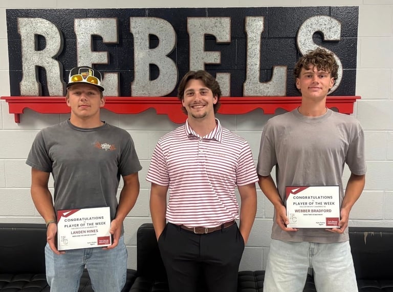 Three men holding certificates stand in front of a Rebels banner in what appears to be a recognition or awards event