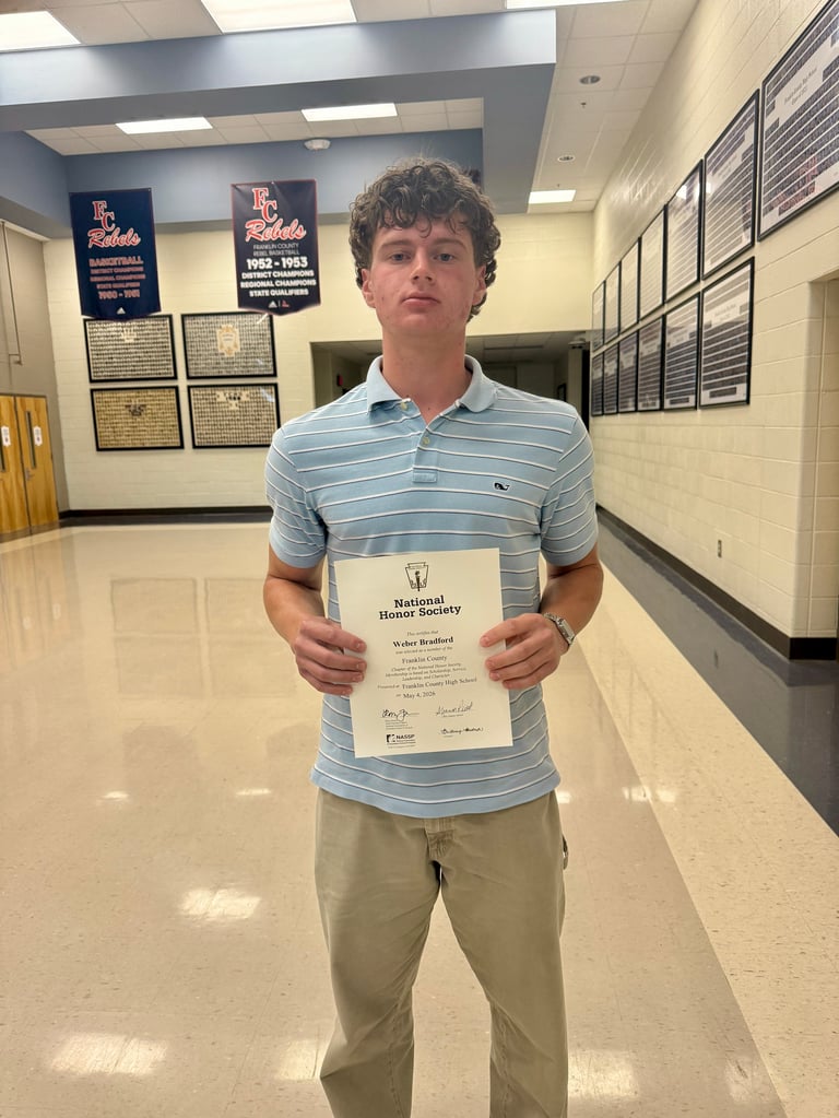 Student holding National Honor Society certificate in school hallway